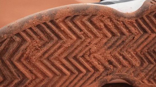 Vue macro des chevrons d'une semelle de tennis terre battue montrant leur profondeur et leur géométrie spécifique