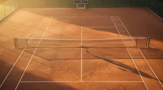 Vue d'ensemble d'un court de tennis avec ombre de joueur débutant face à un tableau de score complexe