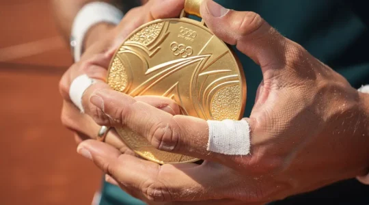Un joueur de tennis tenant une médaille d'or olympique sur un court de tennis avec émotion